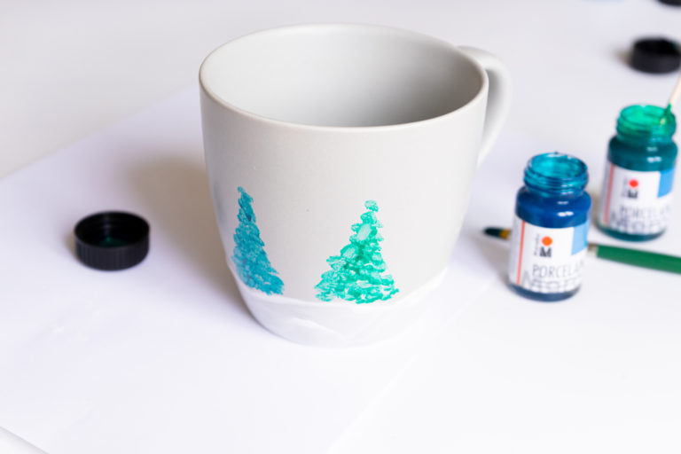 Eine Tasse wird mit einer Winterlandschaft bemalt