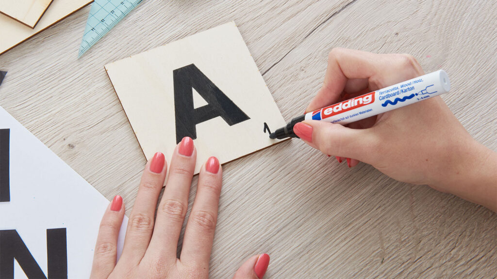 Eine Holzplatte  vom Scrabble wird mit dem Buchstaben A bemalt.