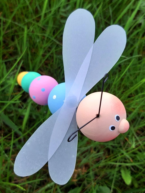 Eine Libelle aus Holzkugeln über einer Grasfläche
