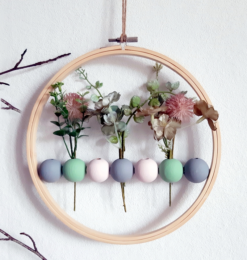 Ein dekorierter Stickrahmen mit bunten Holzkugeln und Blumen