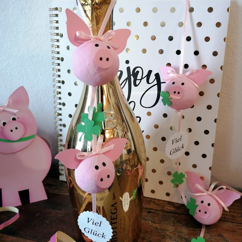 Glückschweine aus wattekugeln an einer Sektflasche