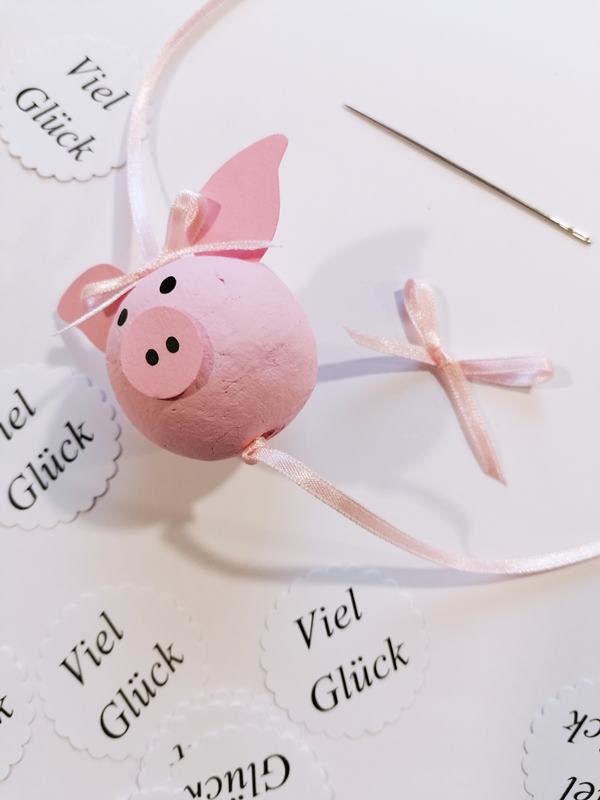 Ein rosafarbenes Glücksschwein mit Button viel Glück