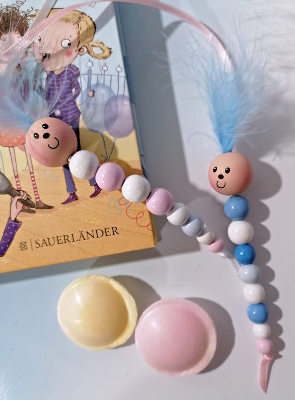 Bücherwurm als Lesezeichen aus rosafarbenen und hellblauen Holzperlen