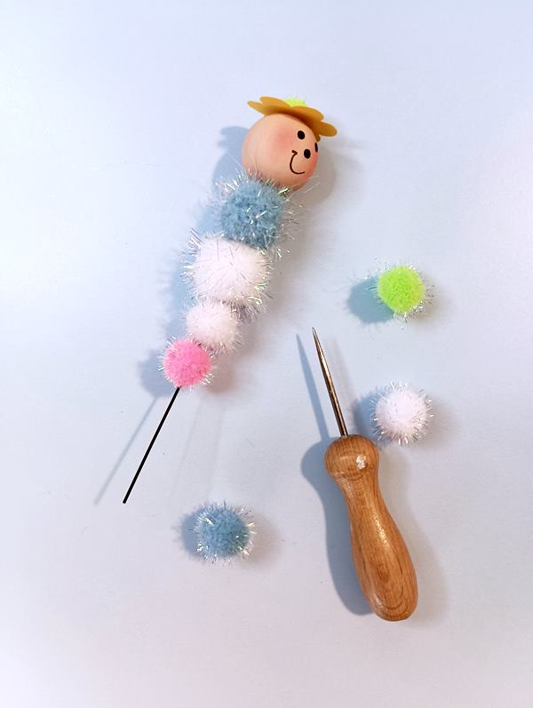 Pompons werden für die Raupen auf einen Draht gefädelt